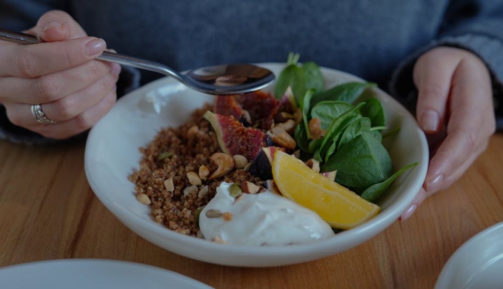 A vibrant brunch bowl with fruit, greens, and nuts for a nutritious meal.