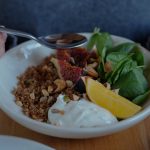 A vibrant brunch bowl with fruit, greens, and nuts for a nutritious meal.