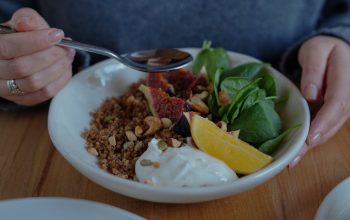 A vibrant brunch bowl with fruit, greens, and nuts for a nutritious meal.